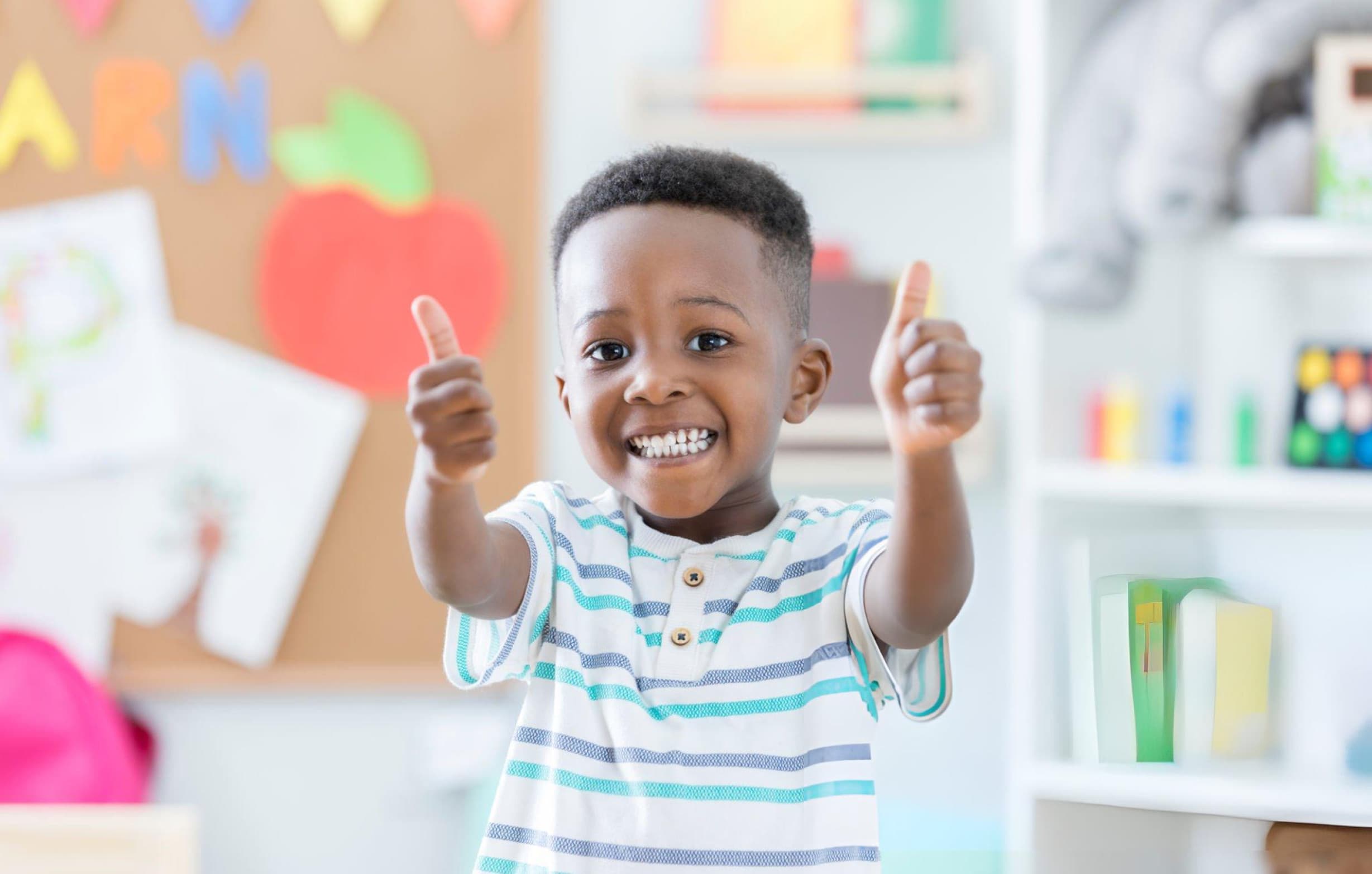 Happy child giving thumbs up in classroom